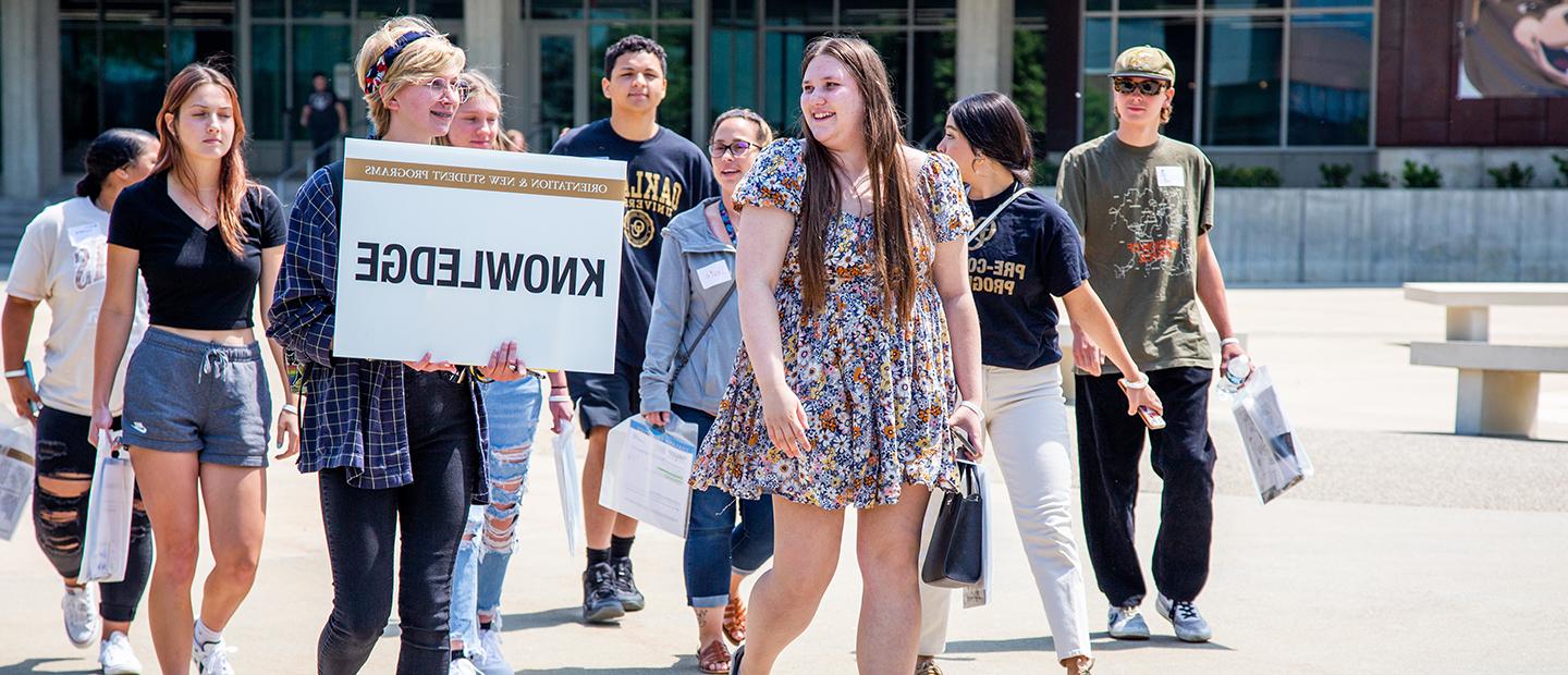 Group of young people walking in a group. One person is holding an 